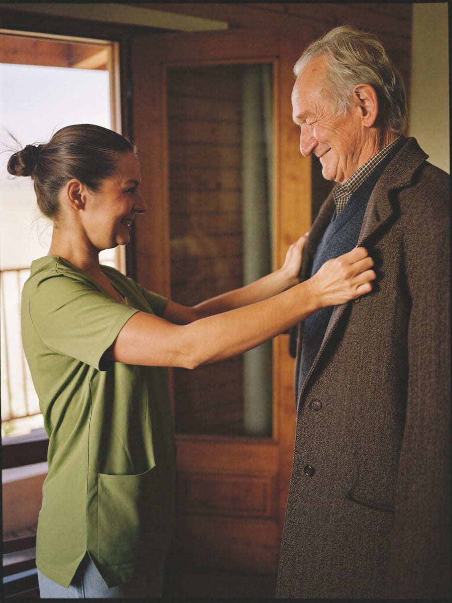 A DoveBridge caregiver helping an older man into his coat at his Winnipeg home